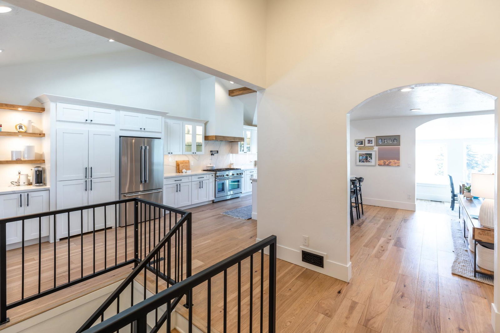 A kitchen with a stainless steel refrigerator, stove, and microwave. The kitchen is white and has a wooden floor.