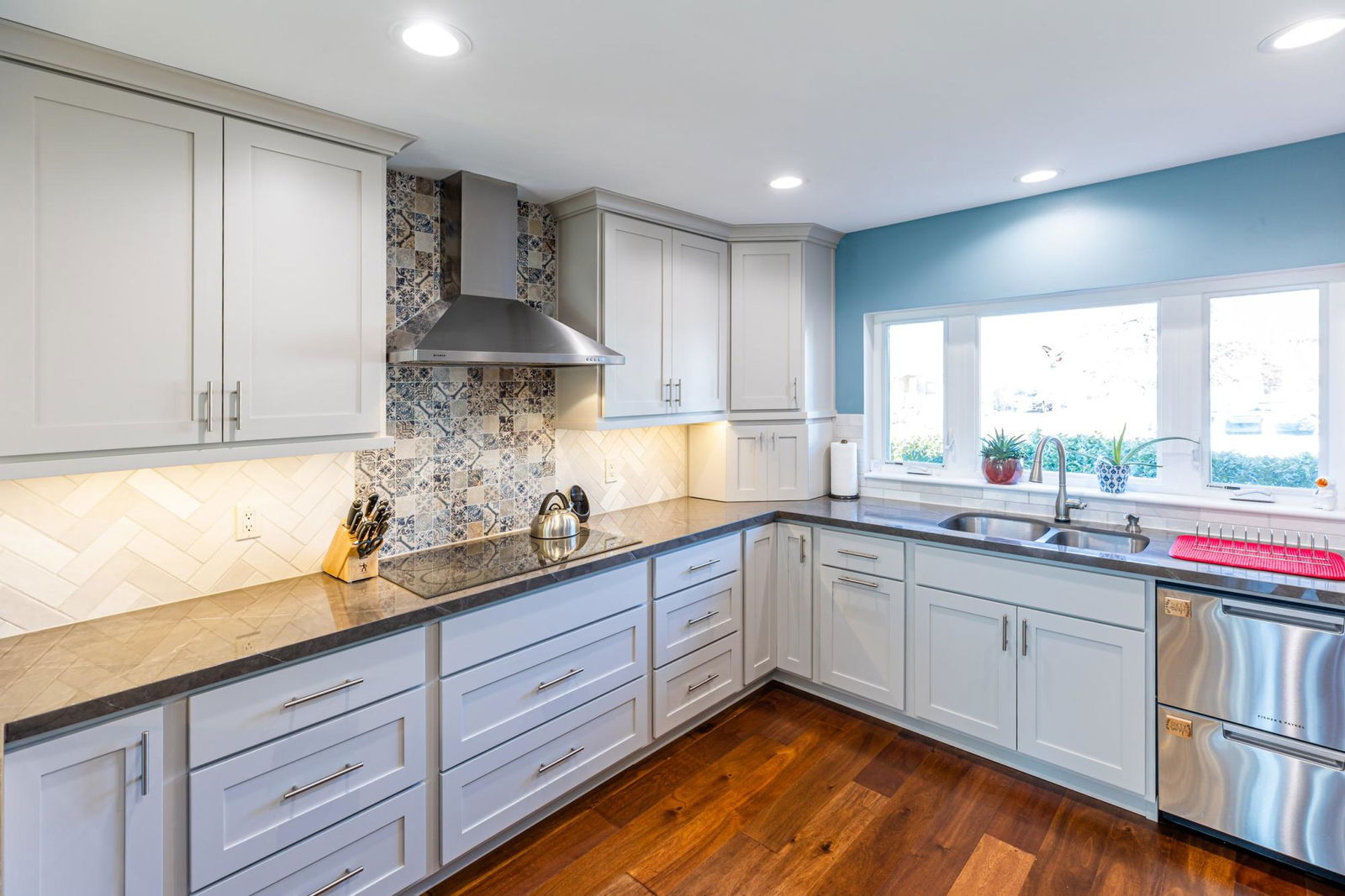 A kitchen with white cabinets and a stainless steel dishwasher