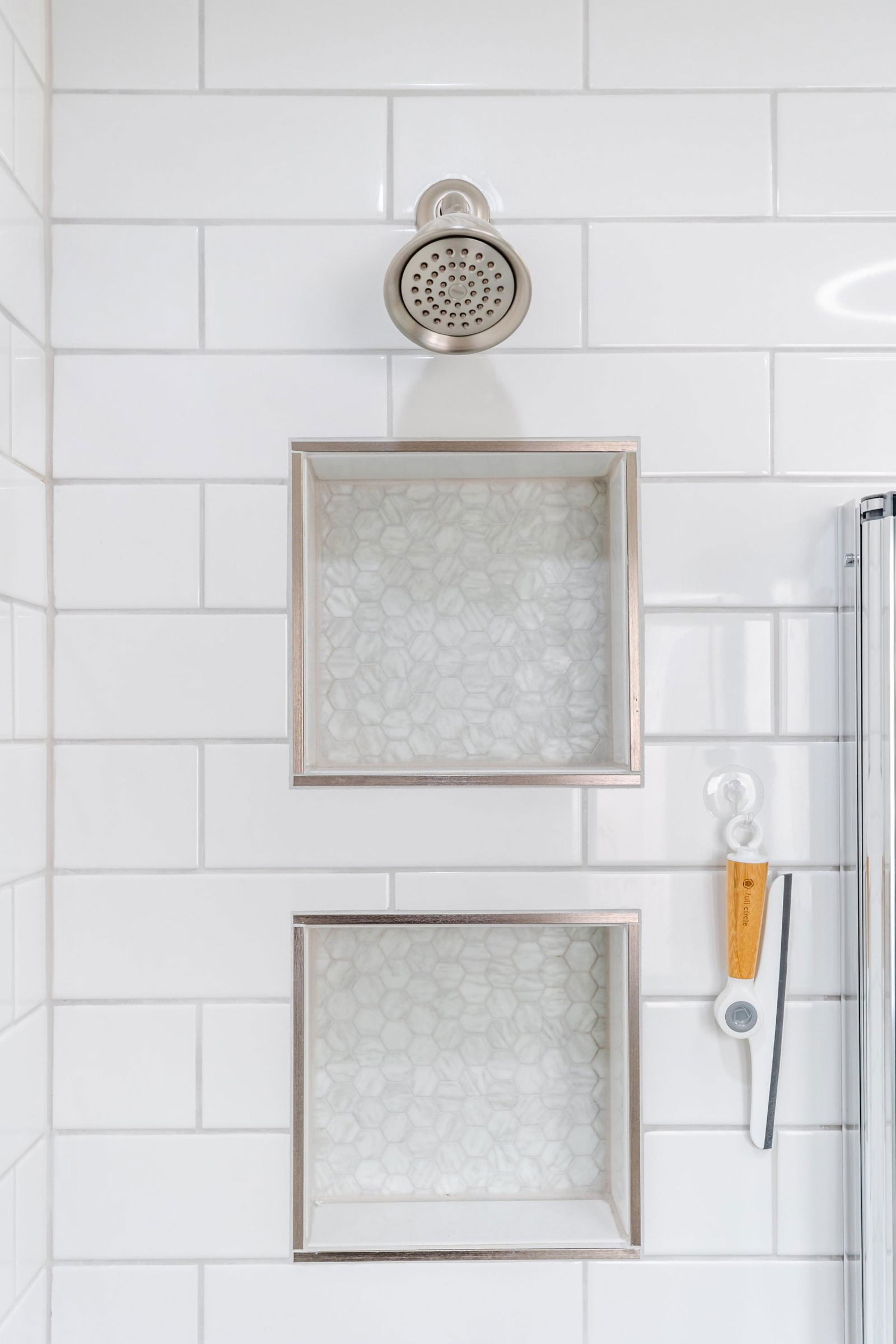 A bathroom with white tile and a shower head