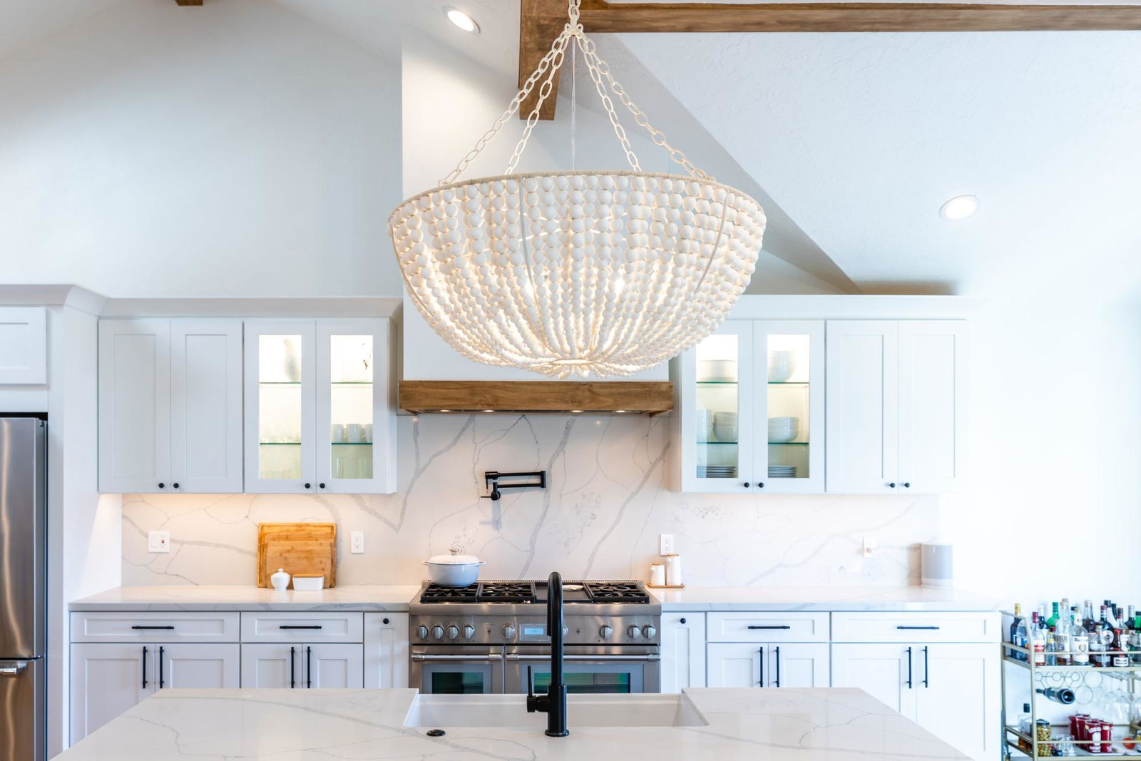 A white kitchen with a chandelier hanging from the ceiling