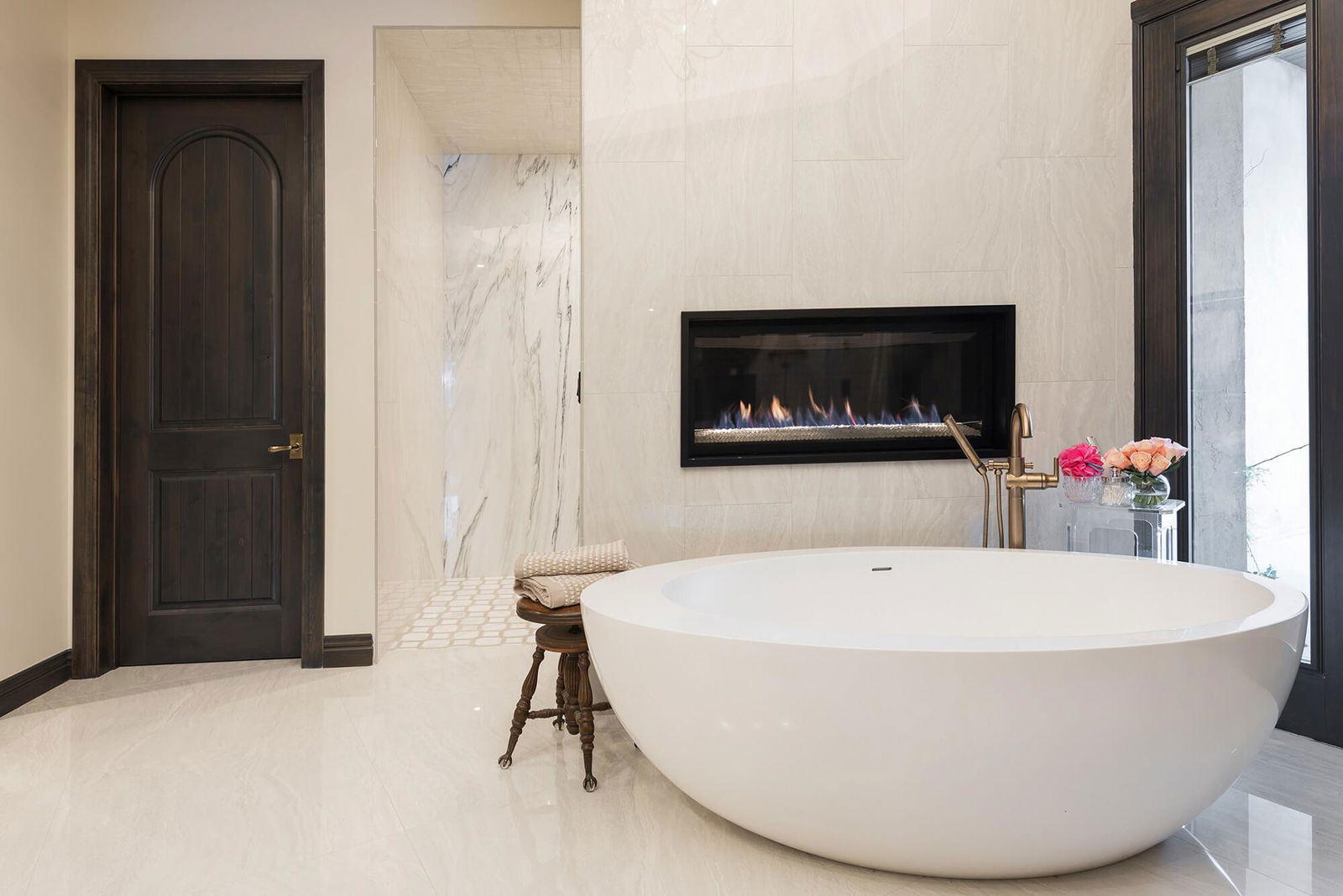 A large white bath tub sitting in a bathroom next to a fireplace