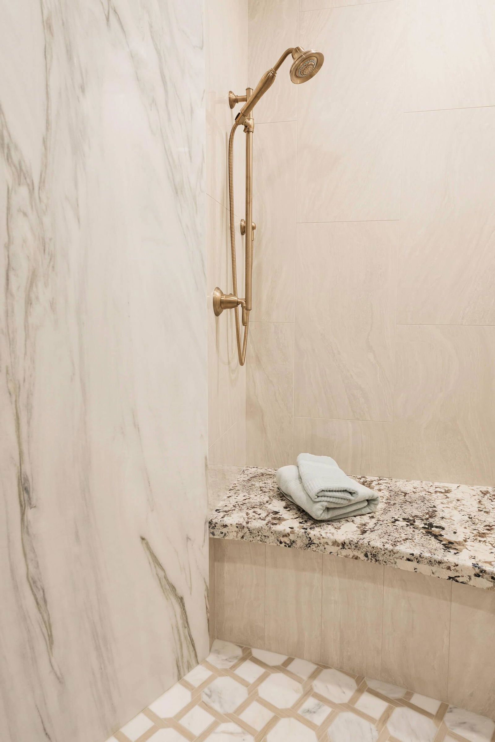 A bathroom with a marble counter top and shower