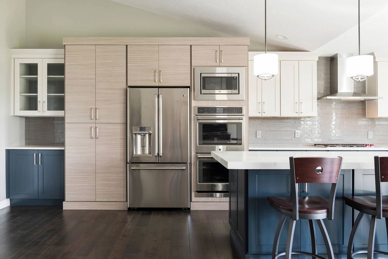 A kitchen with a stove, refrigerator, and bar stools