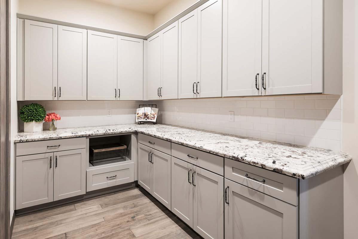 A kitchen with white cabinets and marble counter tops