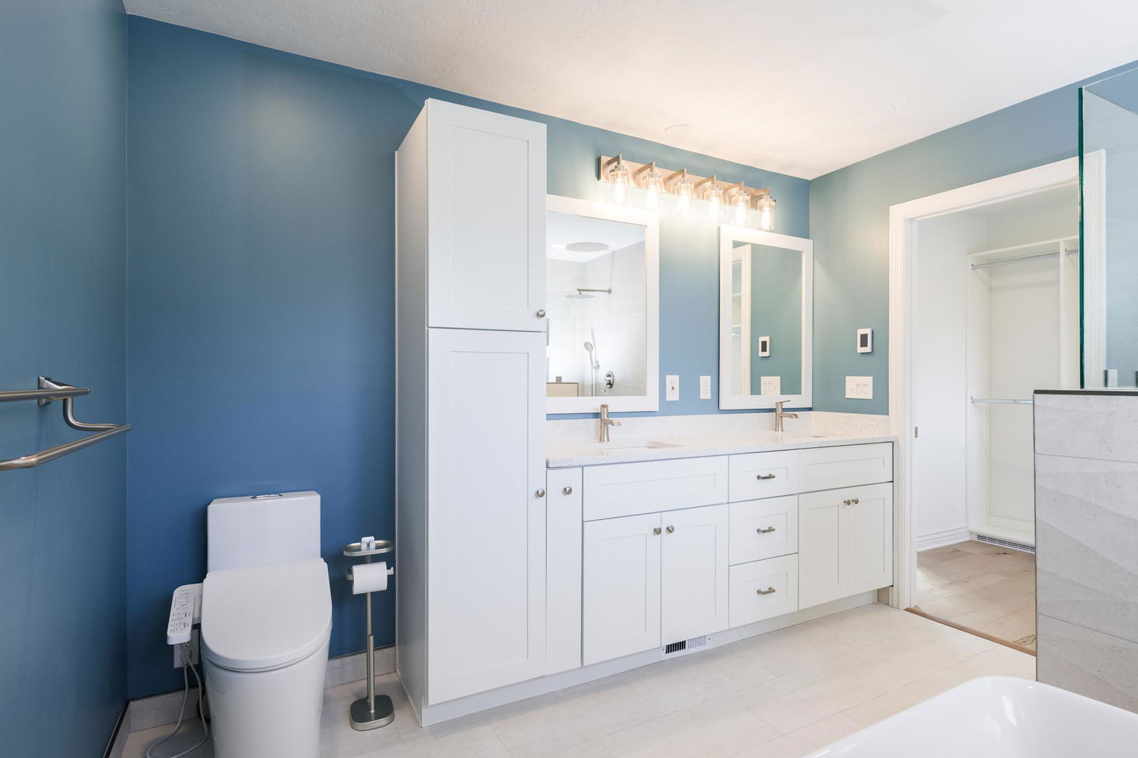 A bathroom with blue walls and white cabinets