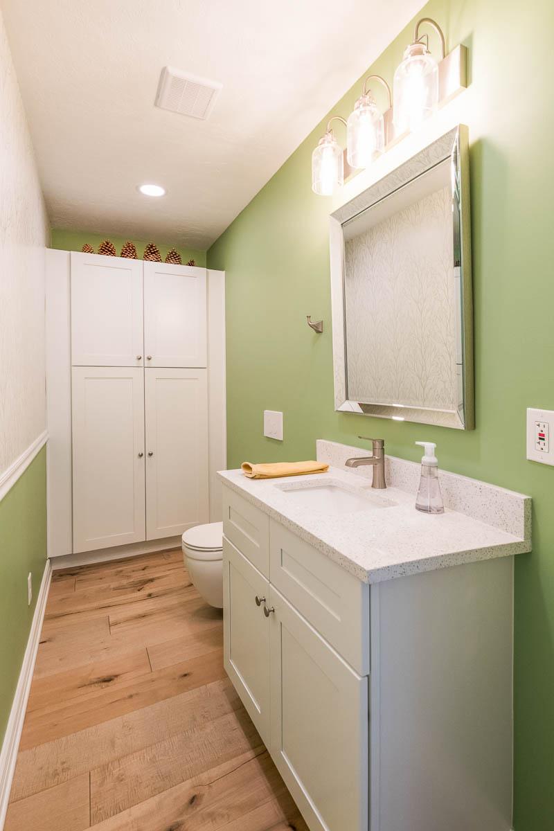 A bathroom with green walls and white cabinets