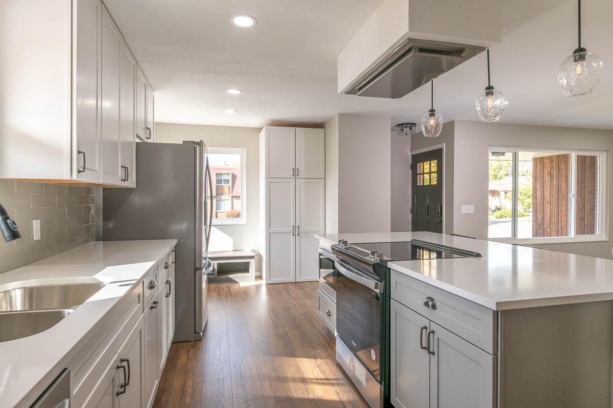 A kitchen with a stove, sink, and refrigerator