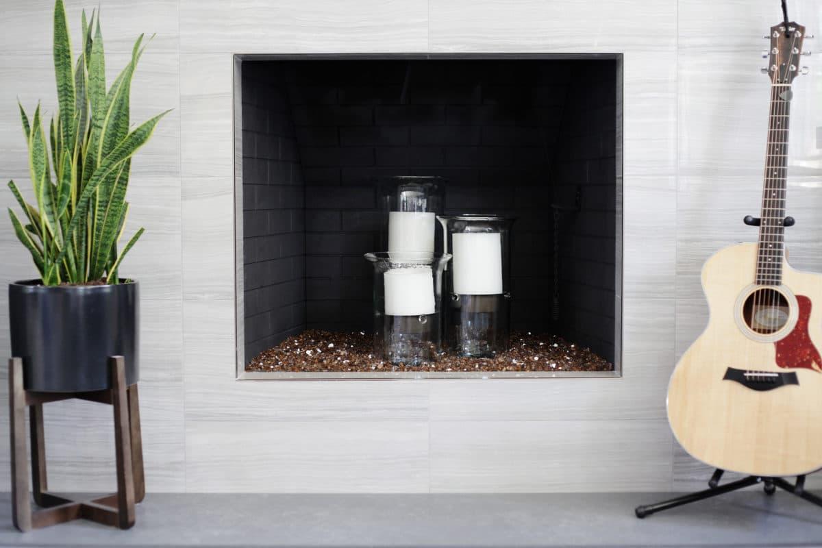 A guitar and a guitar stand in front of a fireplace