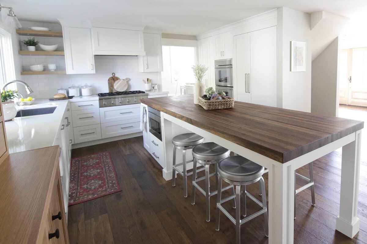 A kitchen with white cabinets and a wooden counter top