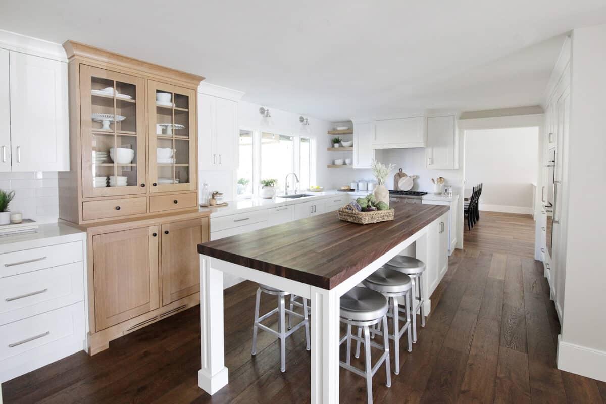 A kitchen with a wooden counter top and white cabinets