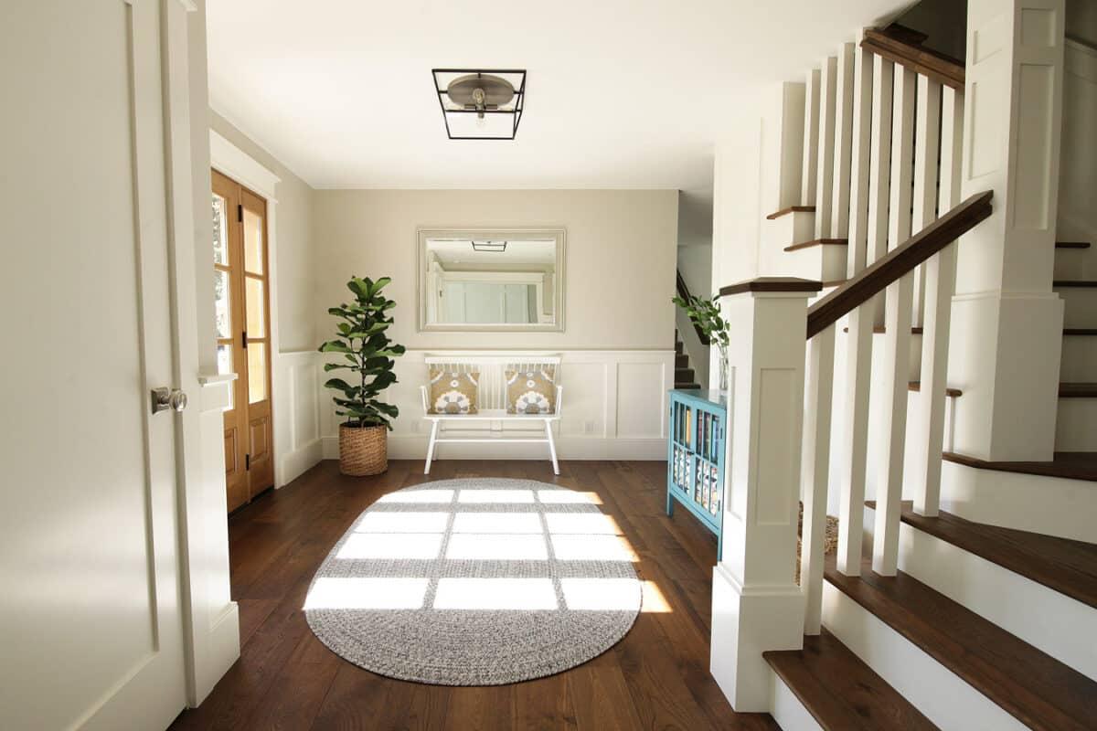 A hallway with a white rug and wooden stairs