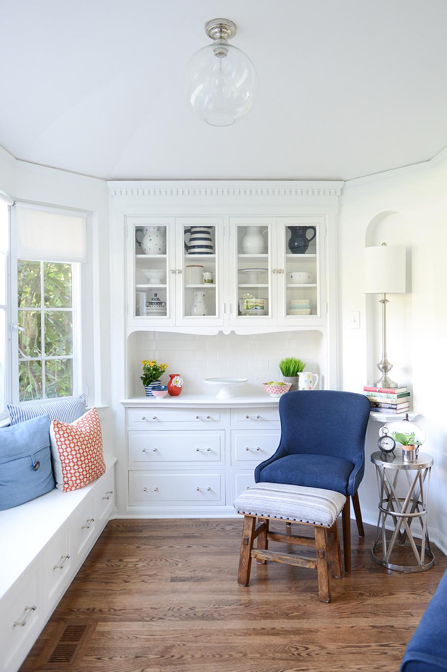 A kitchen with white cabinets and blue chairs