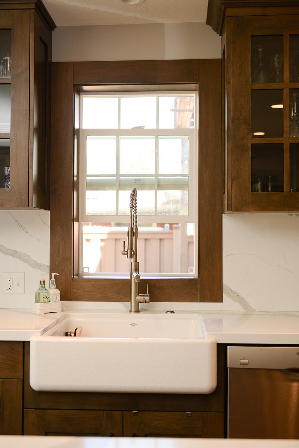 A kitchen with a white sink and wooden cabinets