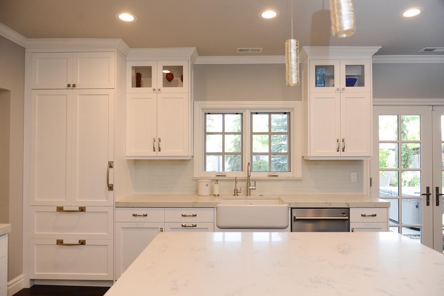 A large kitchen with white cabinets and marble counter tops