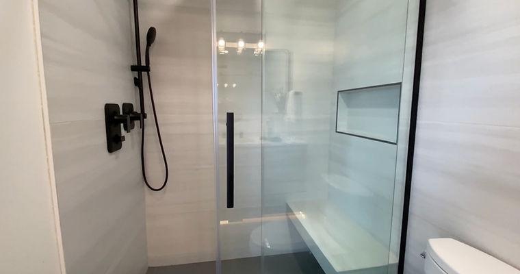 A bathroom with a glass shower door and a toilet