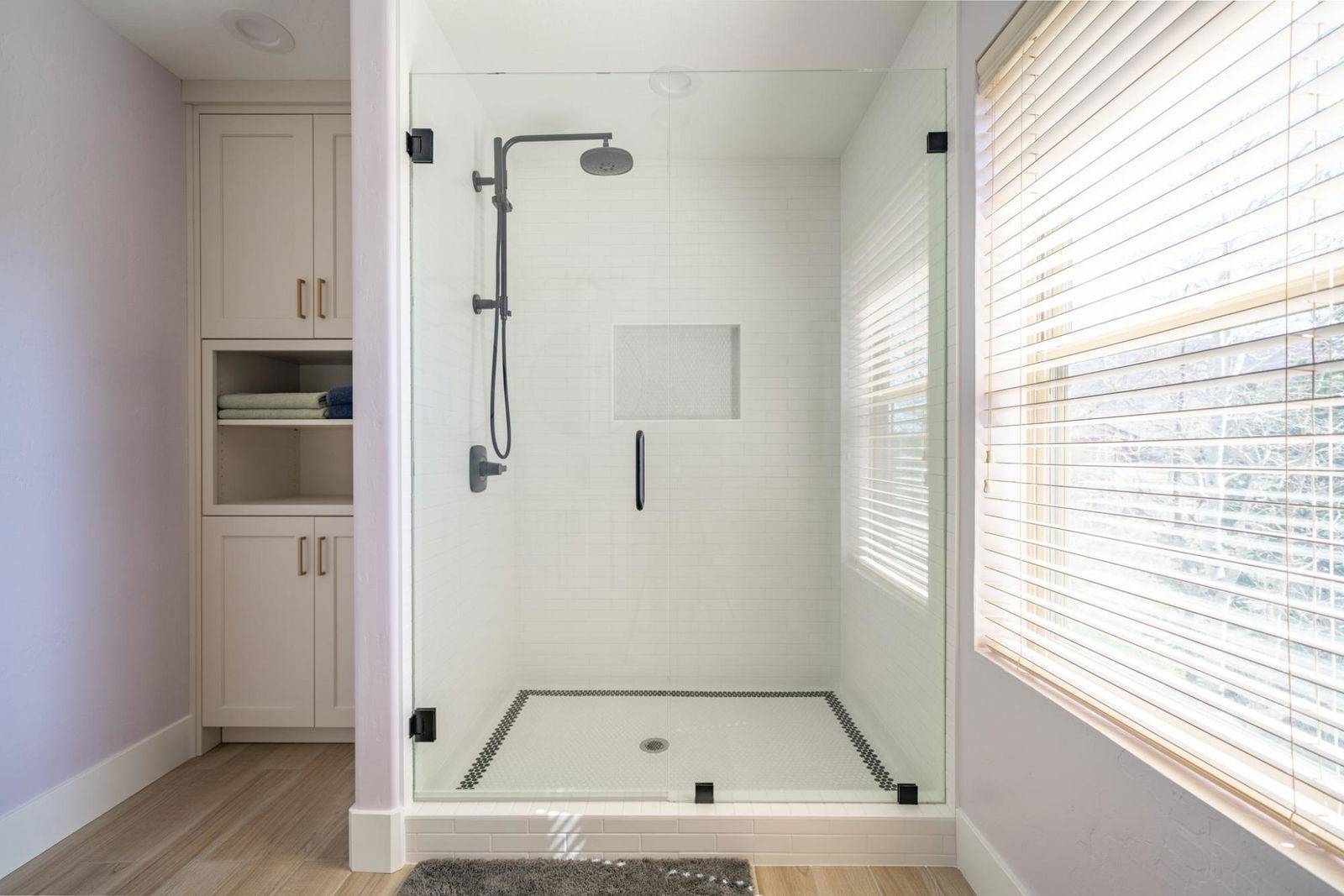 A bathroom with a walk in shower next to a window