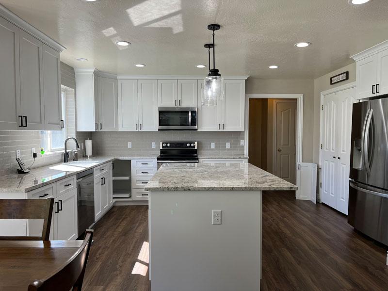 A kitchen with a refrigerator, stove, sink, and dining room table