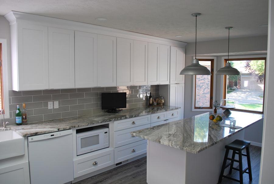 A kitchen with white cabinets and marble counter tops