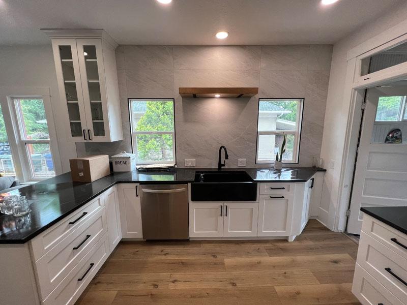 A kitchen with white cabinets and black counter tops