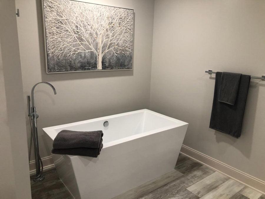 A white bath tub sitting next to a painting on the wall