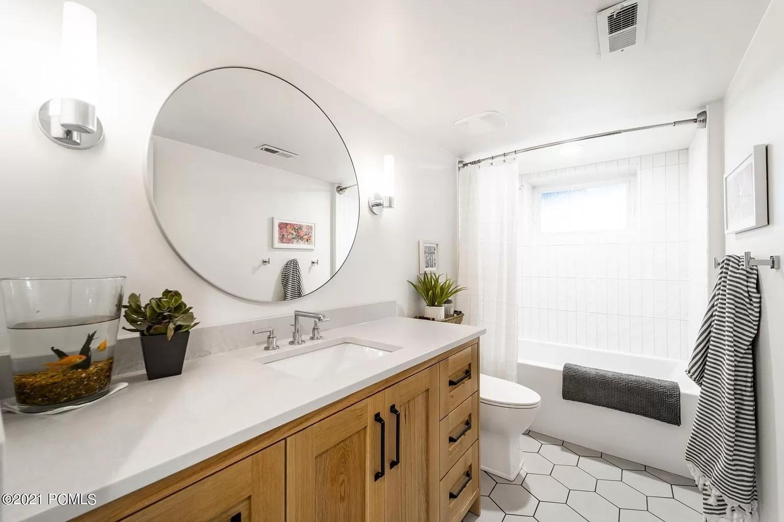 A bathroom with a large round mirror above the sink