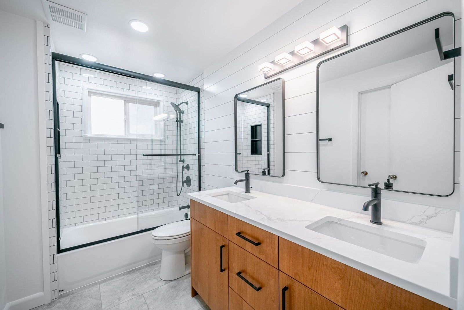 A bathroom with two sinks, a toilet, and a shower