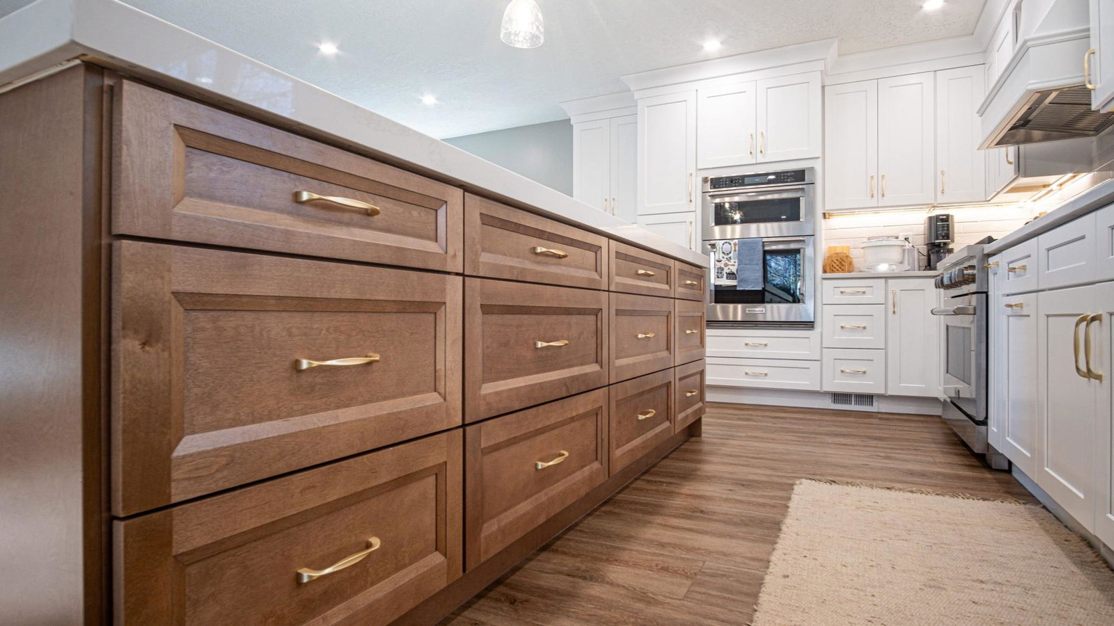 A kitchen with white cabinets and wood floors