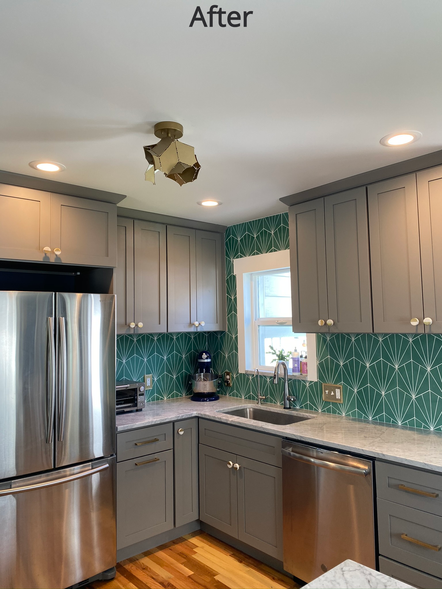 A kitchen with a metallic refrigerator freezer next to a window