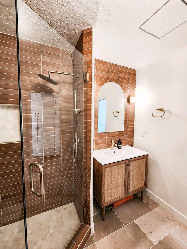 A bathroom with a walk in shower next to a sink