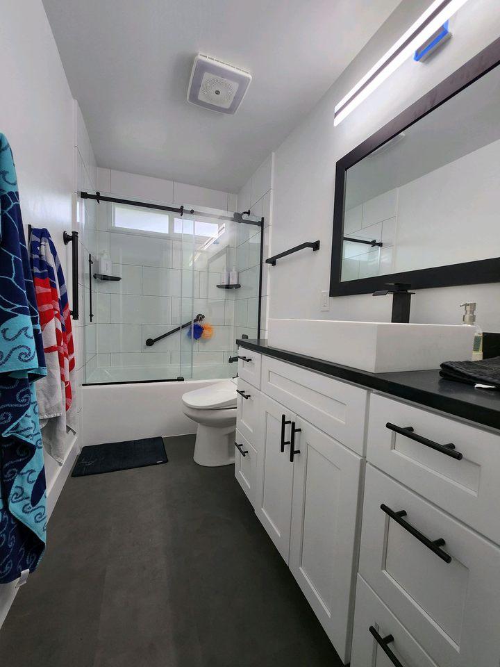 A bathroom with white cabinets and black counter tops