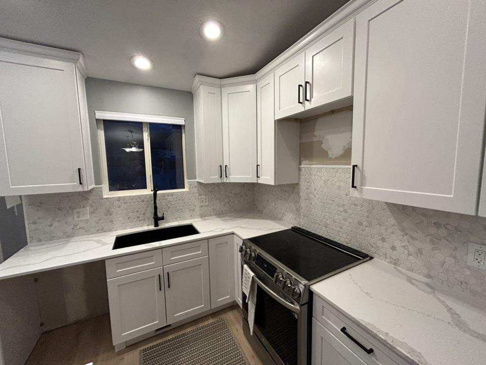 A kitchen with white cabinets and a black stove top oven