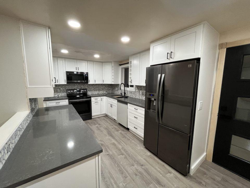 A kitchen with white cabinets and black appliances