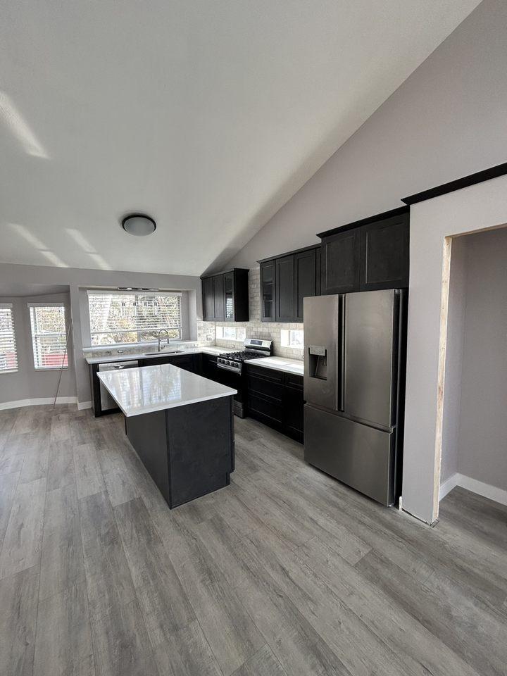 A kitchen with a refrigerator and a stove top oven